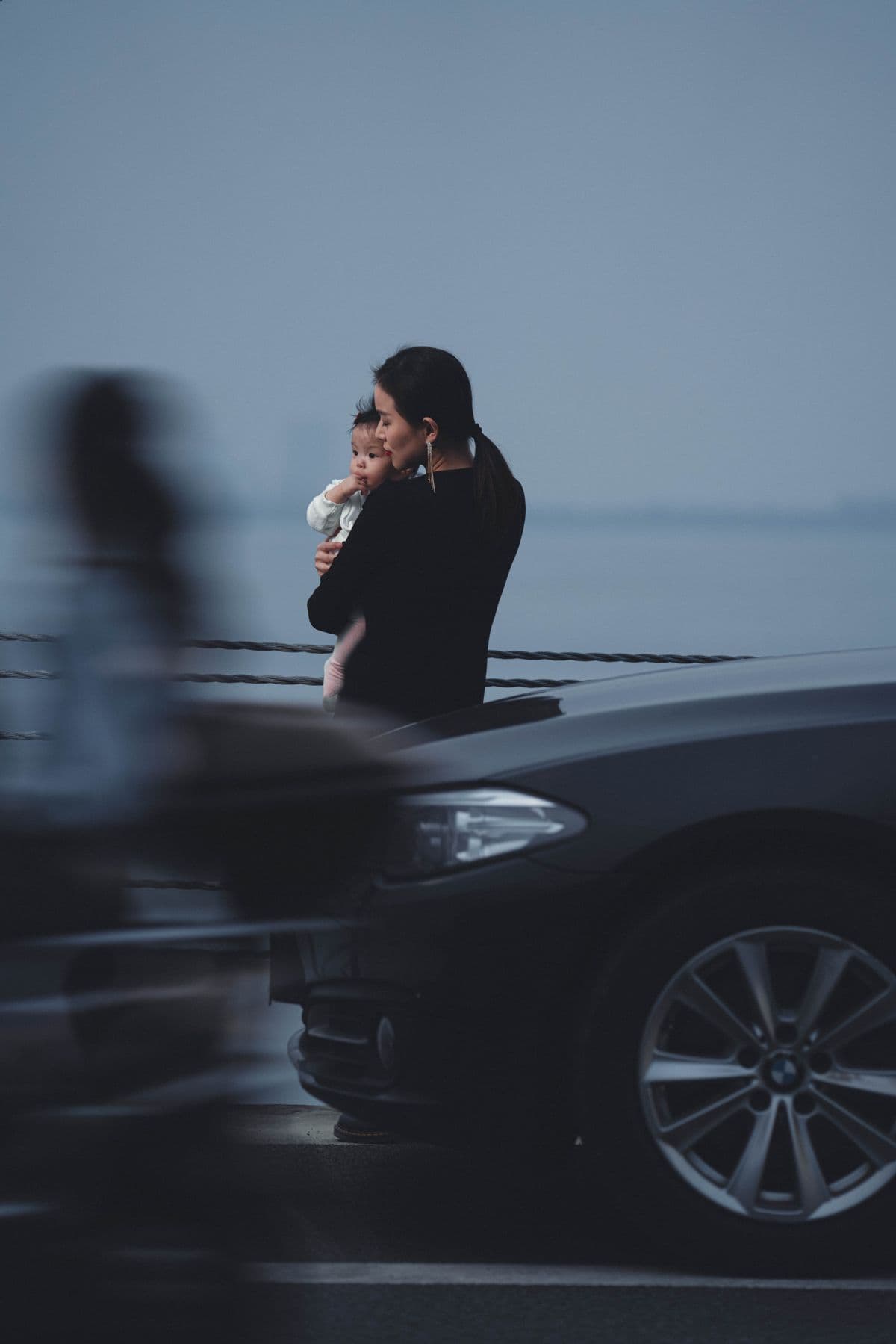 A mother holding her child beside a waterfront street